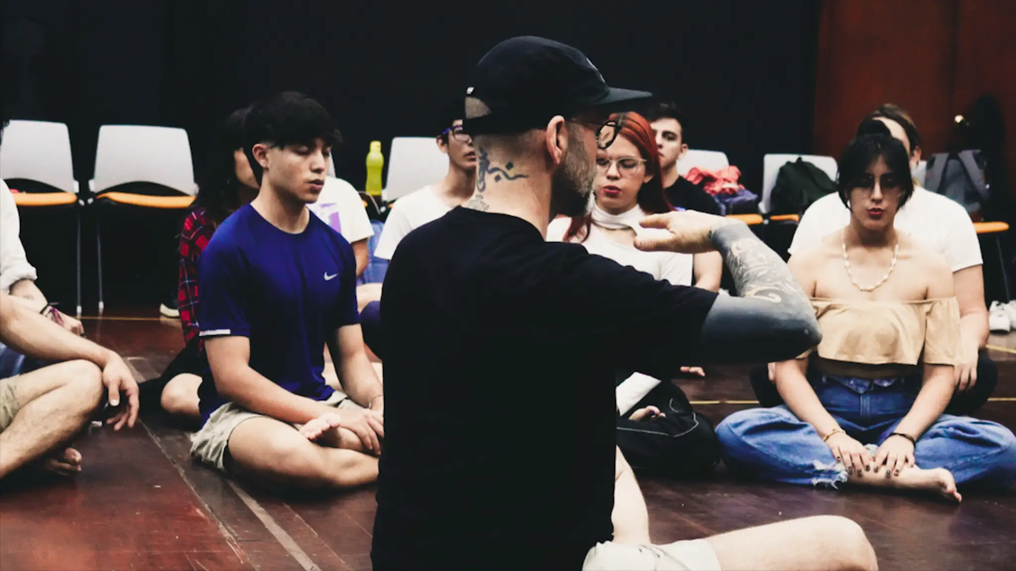 The instructor and students sitting on the floor while the instructor teaches a breathing technique while the students follow intently