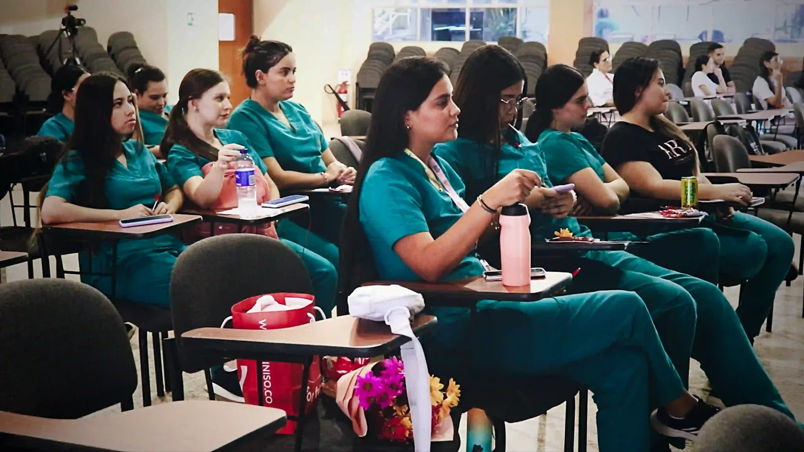 Young women in green medical uniform list in a conference room listening to a presentation