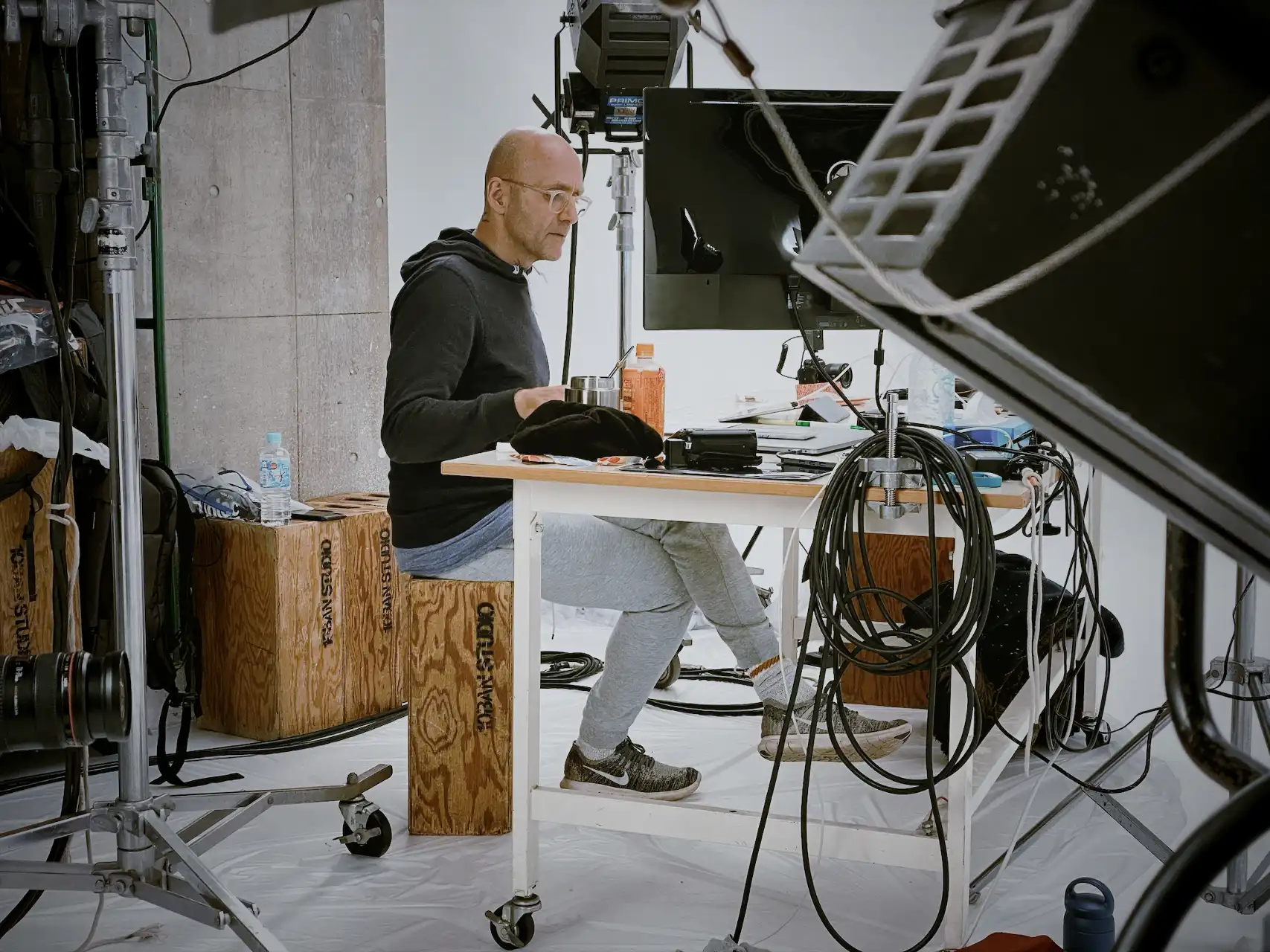 Patrick sitting at a table in a room with a large screen and a large microphone