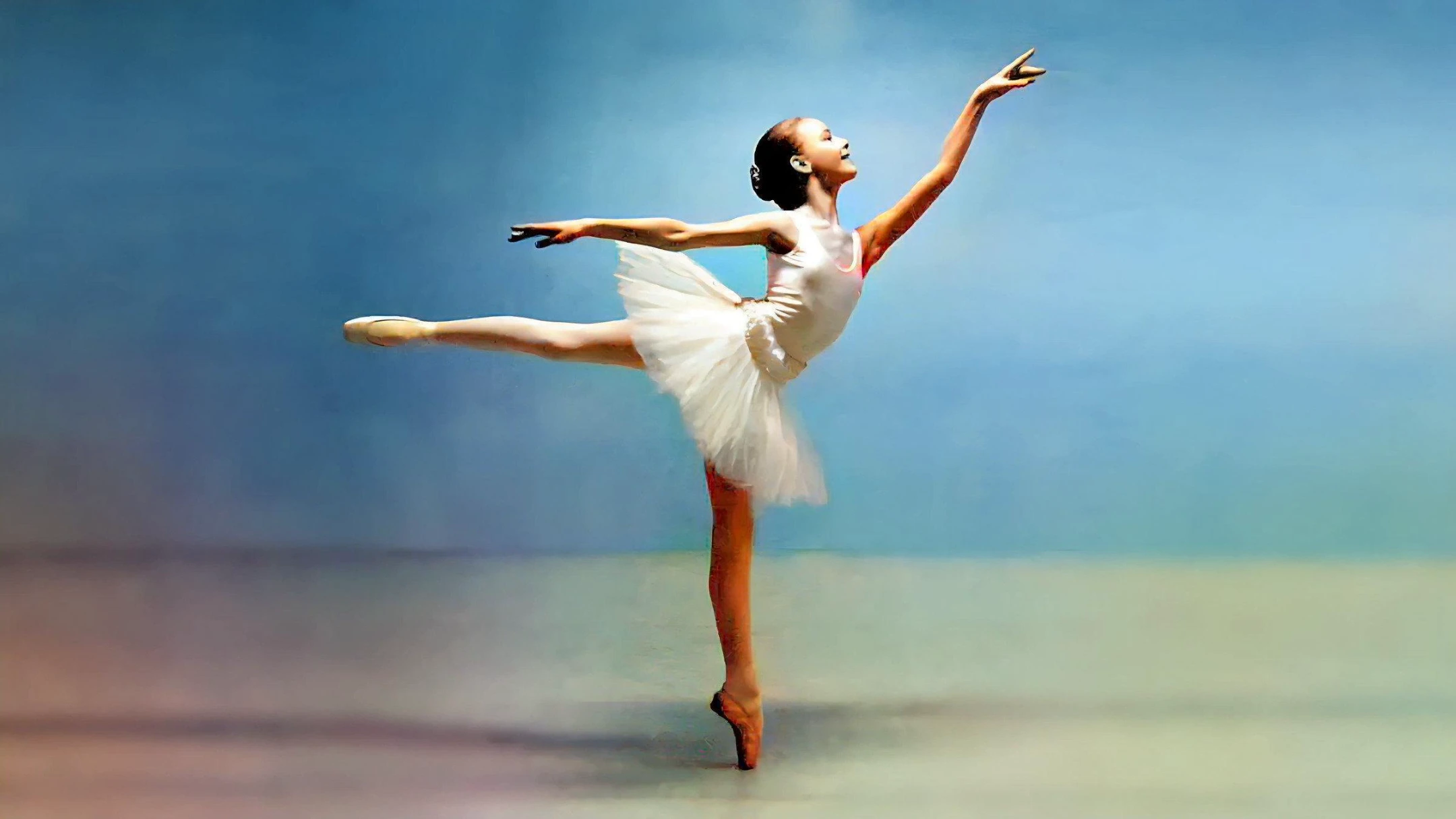 a young ballerina in a white tutu dancing doing an arabesque