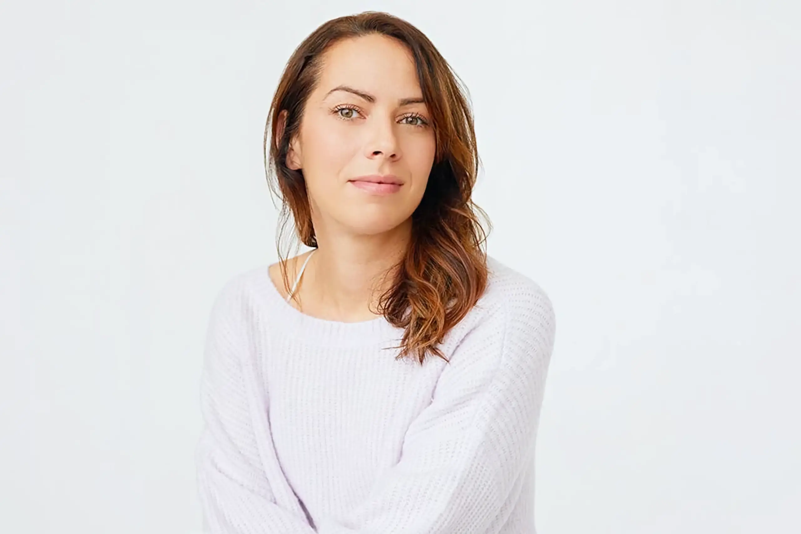 a woman with long brown hair wearing a white sweater