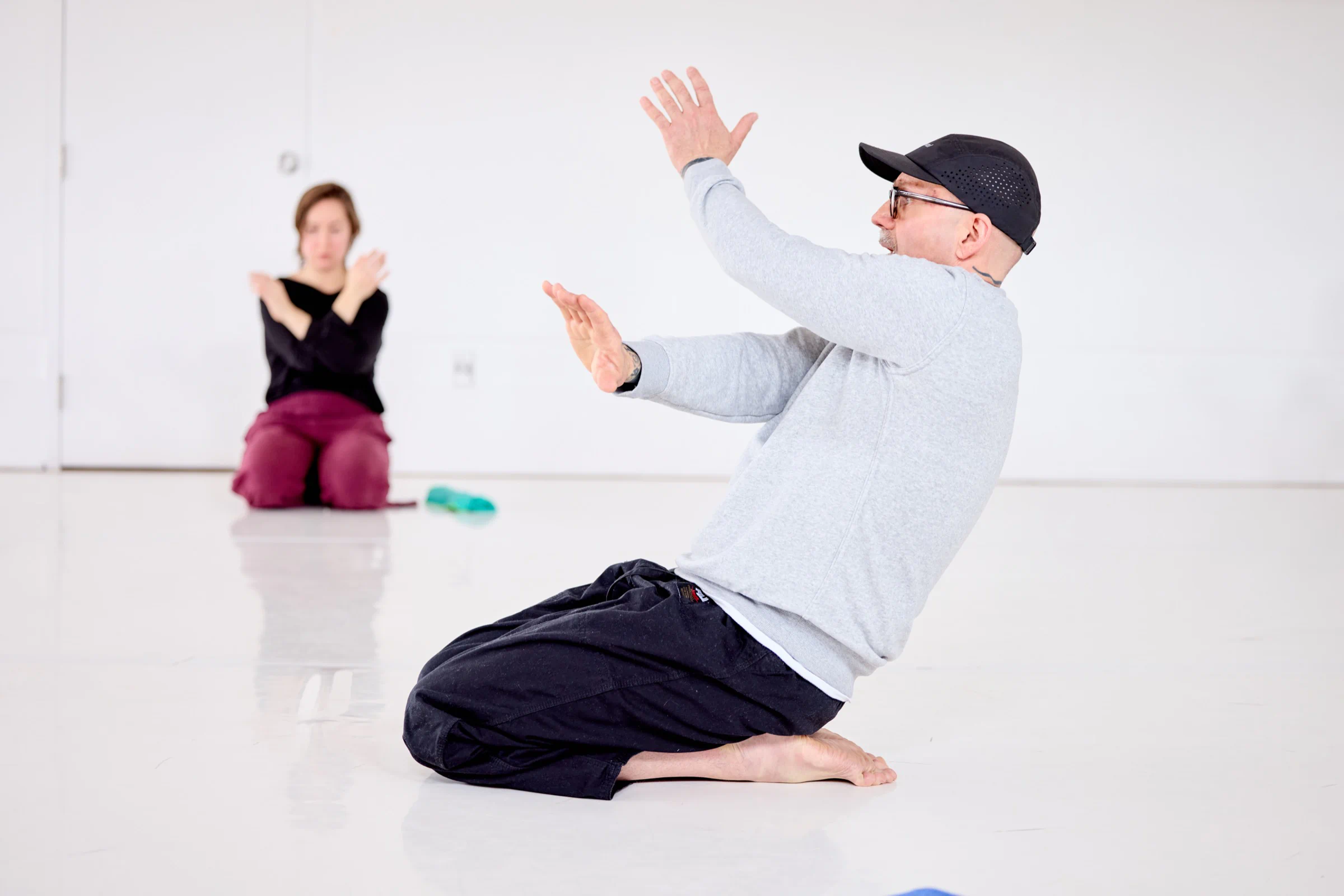 Patrick Oancia demonstrating a kneeling seated form with a participant following along during guided practice at the Winter 2026 Study Group