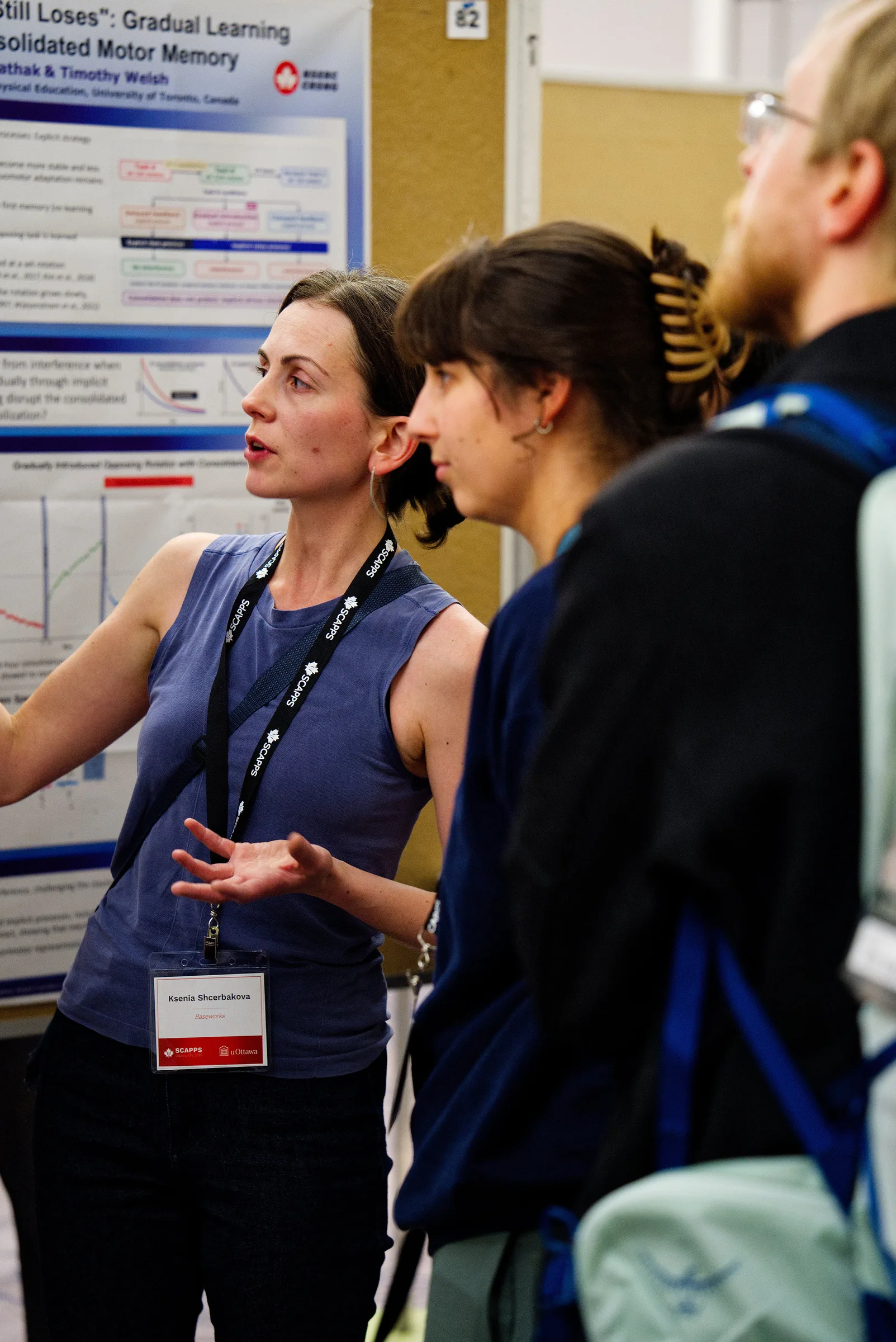 Ksenia Asia Shcherbakova talks with two conference attendees in the SCAPPS 2026 poster hall.