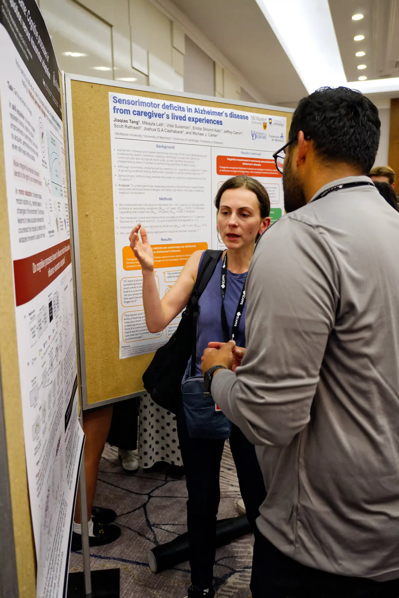 Ksenia Asia Shcherbakova talks with a visitor in front of another presenter's poster during the SCAPPS 2026 poster session.