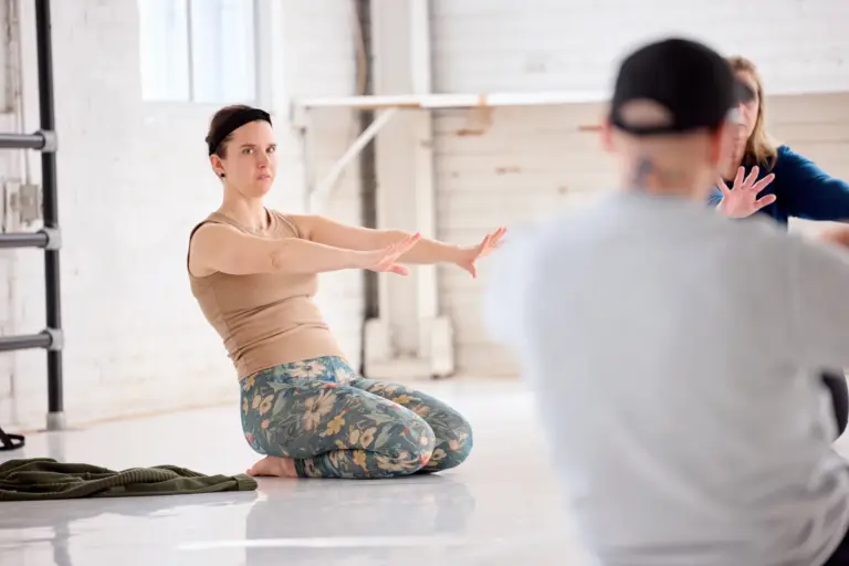A participant kneeling with arms extended forward during a Baseworks Winter 2026 Study Group session in Montreal